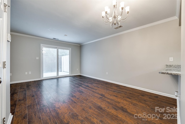 spare room featuring crown molding, dark hardwood / wood-style floors, and a chandelier