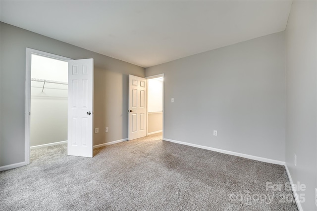 unfurnished bedroom featuring a spacious closet, carpet floors, and a closet