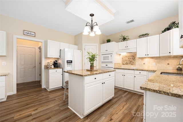 kitchen with pendant lighting, sink, white cabinets, a center island, and white appliances