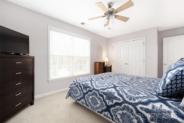 bedroom with light carpet, ceiling fan, and a closet