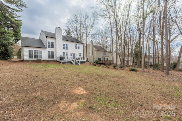 back of property with a wooden deck and a lawn