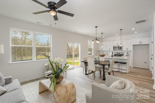 living room featuring ceiling fan, sink, and light hardwood / wood-style floors