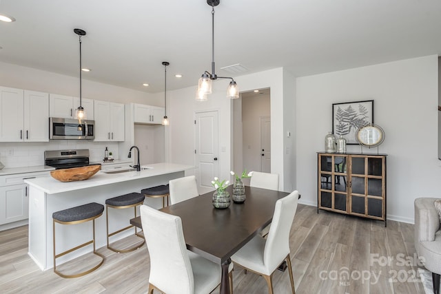 dining room featuring sink and light hardwood / wood-style flooring