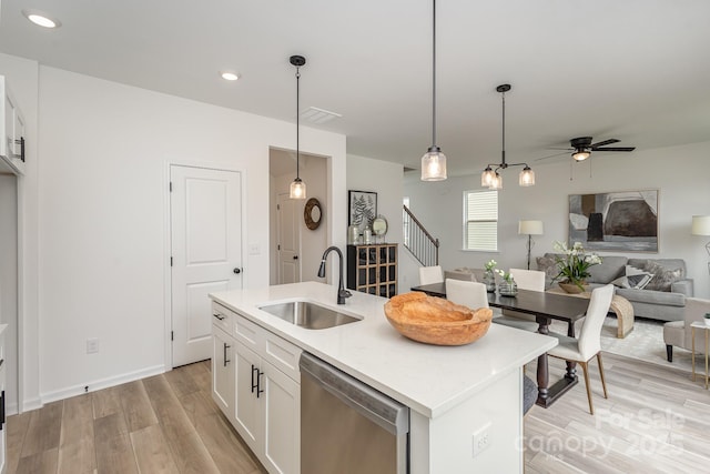 kitchen with white cabinetry, stainless steel dishwasher, an island with sink, and sink