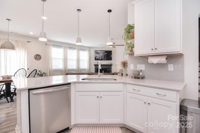 kitchen with decorative light fixtures, backsplash, white cabinetry, a sink, and dishwasher