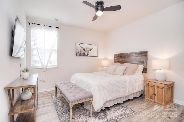 bedroom featuring light wood-style floors, baseboards, visible vents, and a ceiling fan