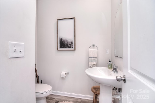 bathroom with toilet, baseboards, and wood finished floors