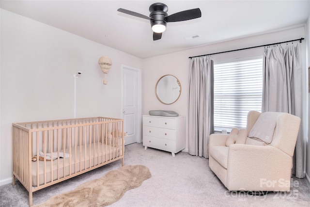 carpeted bedroom with a nursery area, ceiling fan, and visible vents