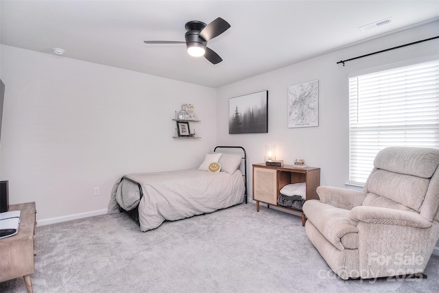 carpeted bedroom featuring baseboards, multiple windows, visible vents, and a ceiling fan