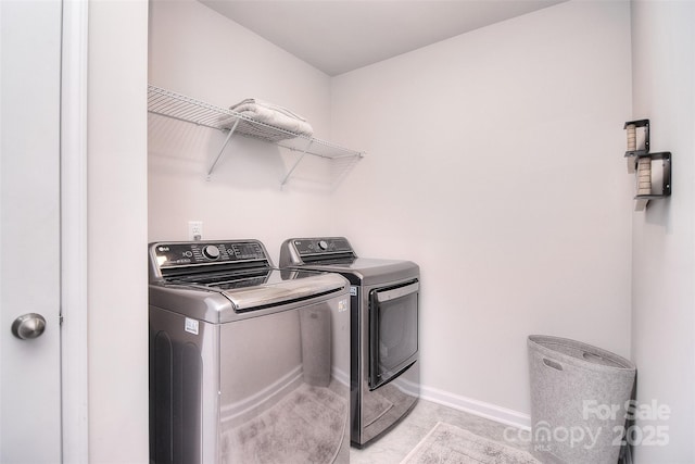 clothes washing area featuring laundry area, light tile patterned floors, baseboards, and washing machine and clothes dryer