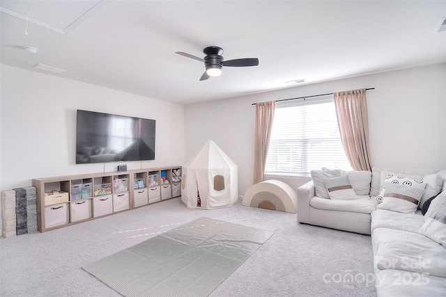 living room with visible vents, ceiling fan, carpet flooring, and attic access