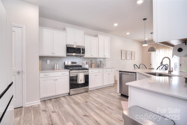 kitchen with a sink, decorative backsplash, appliances with stainless steel finishes, and white cabinetry