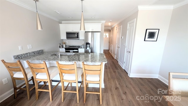 kitchen with appliances with stainless steel finishes, white cabinetry, sink, kitchen peninsula, and light stone countertops