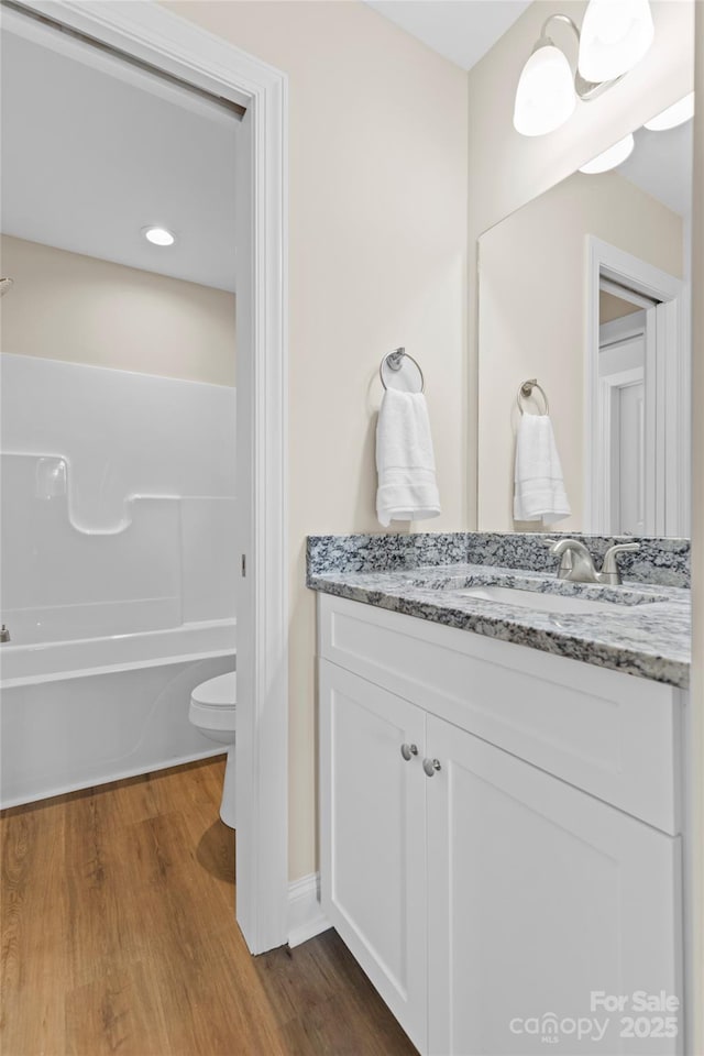 full bathroom featuring vanity, hardwood / wood-style floors, shower / bathtub combination, and toilet