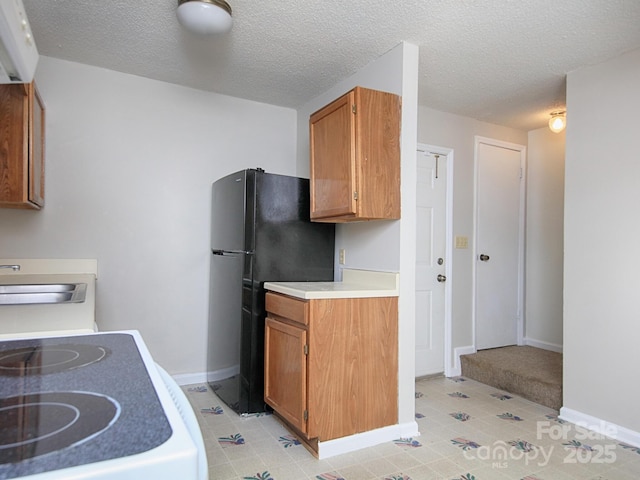 kitchen featuring a sink, baseboards, light countertops, brown cabinetry, and white range with electric cooktop