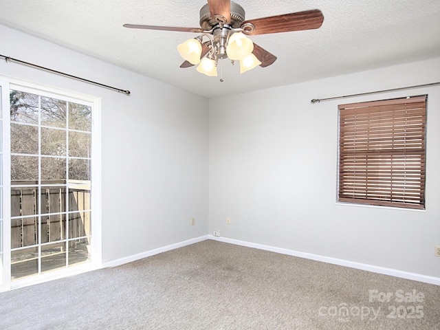 spare room with a textured ceiling, carpet floors, a ceiling fan, and baseboards