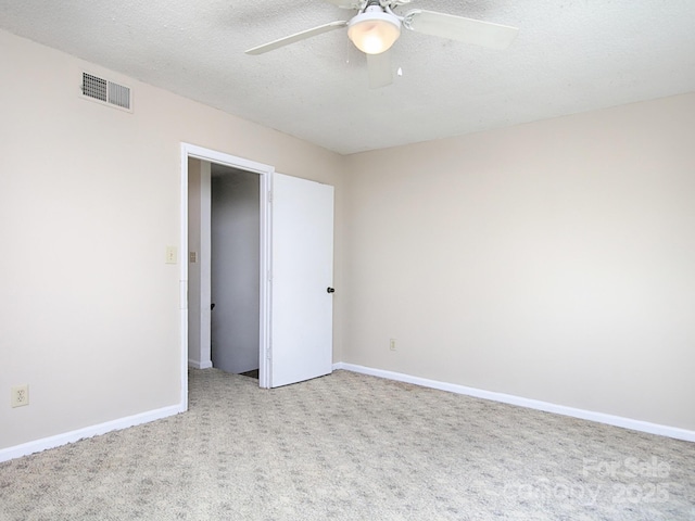 carpeted empty room with ceiling fan, a textured ceiling, visible vents, and baseboards