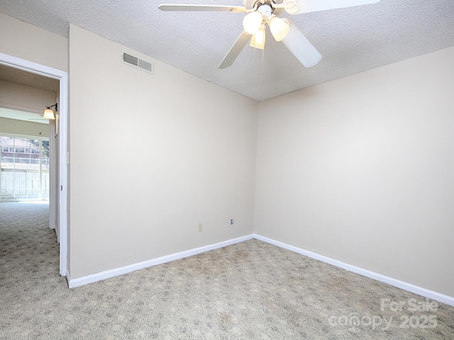 unfurnished room with baseboards, carpet, visible vents, and a textured ceiling