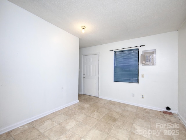 empty room featuring a textured ceiling and baseboards