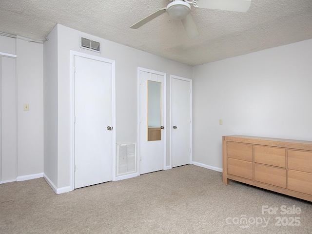 unfurnished bedroom featuring baseboards, light colored carpet, visible vents, and a textured ceiling