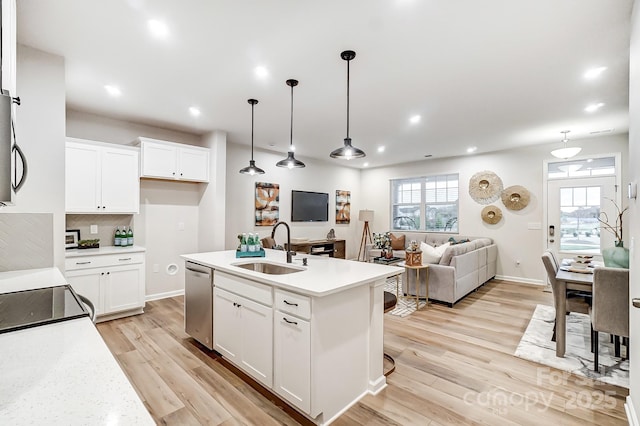 kitchen with stainless steel dishwasher, decorative light fixtures, sink, and white cabinets