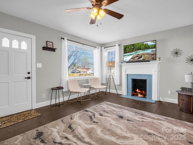 foyer entrance with a fireplace, dark wood finished floors, a ceiling fan, and baseboards