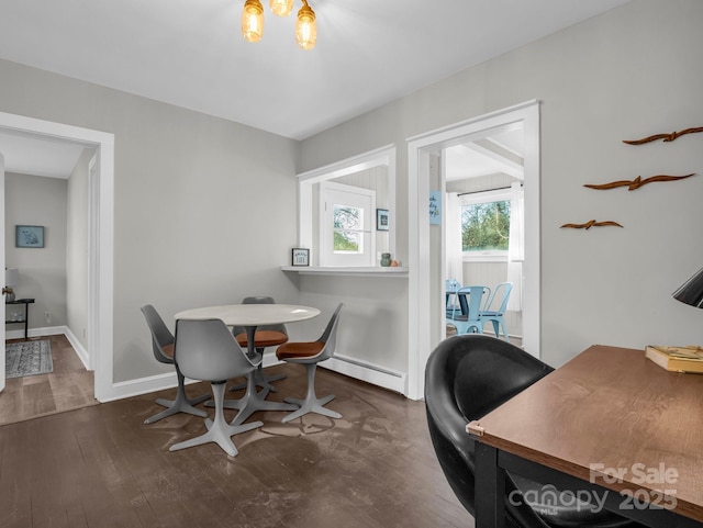 dining room with dark wood-style flooring, a baseboard radiator, an inviting chandelier, and baseboards