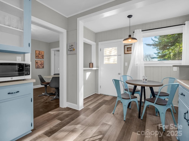 dining space with crown molding, light wood-style flooring, and baseboards