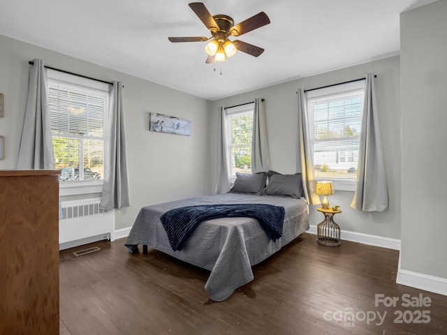 bedroom featuring radiator heating unit, dark wood finished floors, visible vents, and baseboards