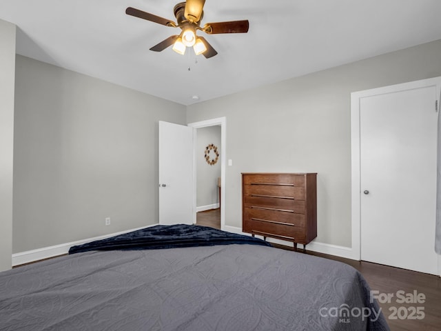 unfurnished bedroom with dark wood-style flooring, a ceiling fan, and baseboards