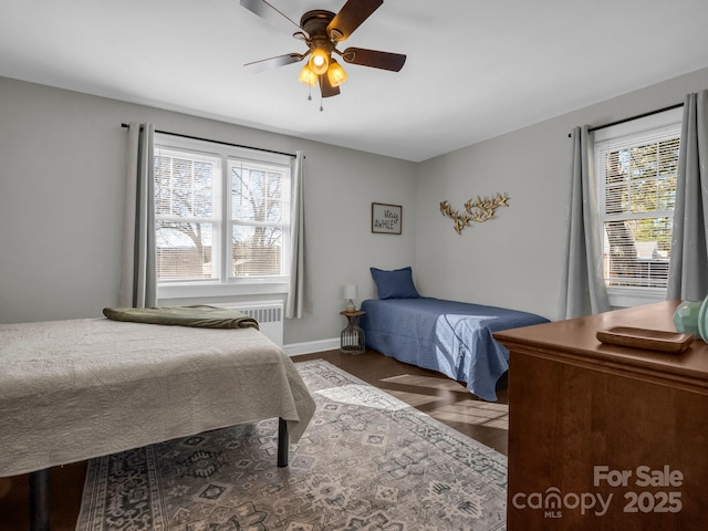 bedroom with ceiling fan, baseboards, dark wood-style floors, and radiator