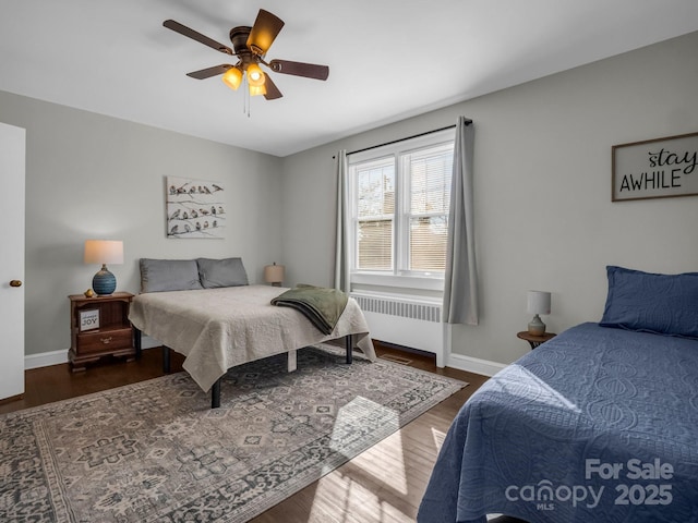 bedroom featuring a ceiling fan, radiator heating unit, baseboards, and dark wood-style flooring