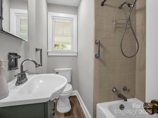 full bath with shower / bath combination, toilet, a sink, wood finished floors, and baseboards