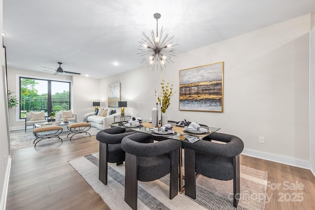 dining area featuring hardwood / wood-style flooring and ceiling fan with notable chandelier