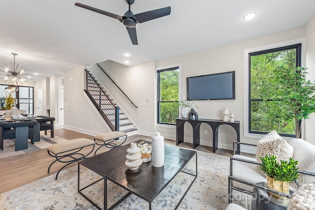 living room with wood-type flooring and ceiling fan with notable chandelier