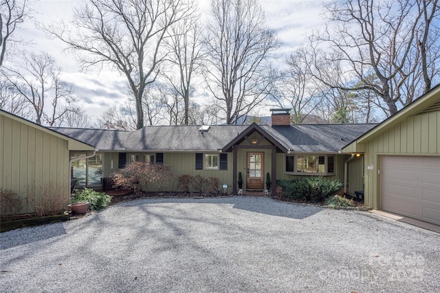 ranch-style house with driveway, roof with shingles, an attached garage, and a chimney