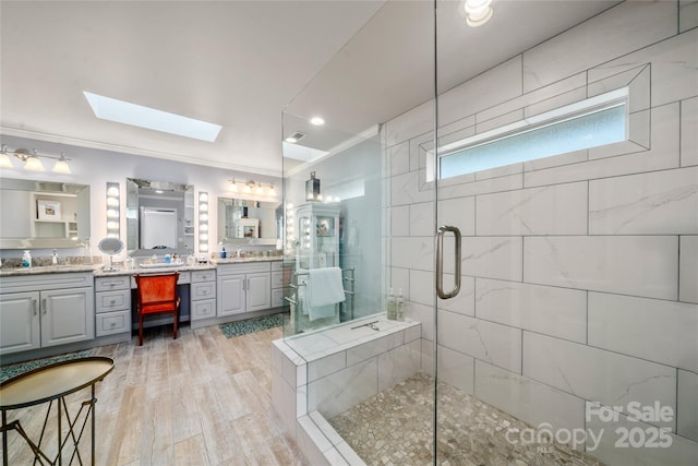 bathroom with ornamental molding, a stall shower, vanity, and a skylight