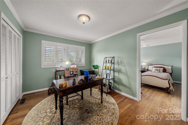 home office featuring ornamental molding, baseboards, wood finished floors, and visible vents