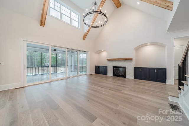 unfurnished living room featuring a notable chandelier, high vaulted ceiling, beamed ceiling, and light wood-type flooring