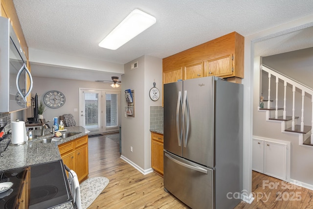 kitchen with ceiling fan, appliances with stainless steel finishes, light hardwood / wood-style flooring, and a textured ceiling