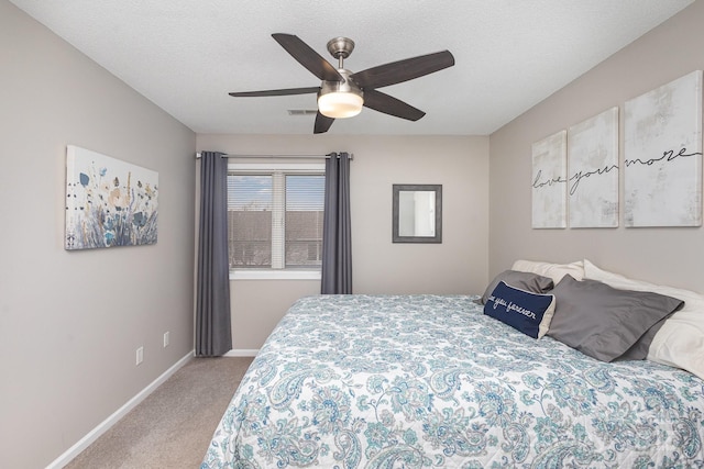 bedroom with ceiling fan, light colored carpet, and a textured ceiling