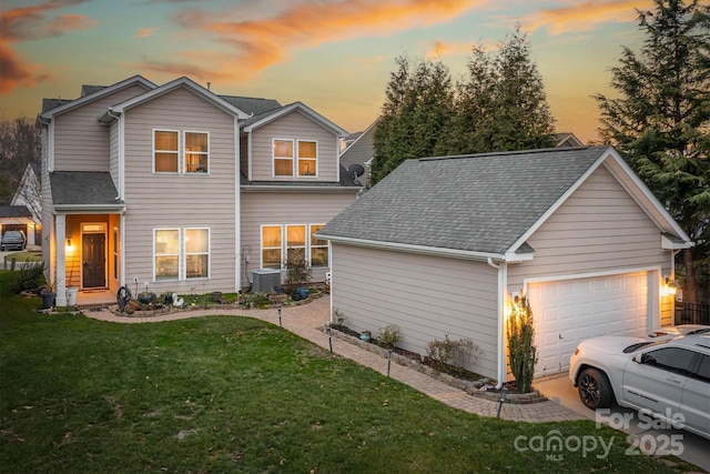 view of front of home with a garage, a shingled roof, central AC unit, and a lawn