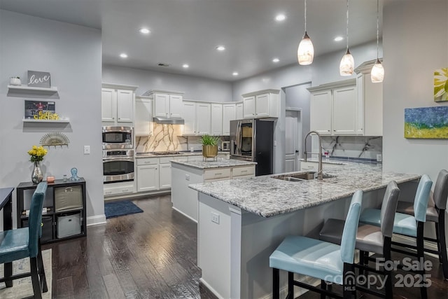 kitchen featuring a breakfast bar, decorative light fixtures, a peninsula, light stone countertops, and stainless steel appliances