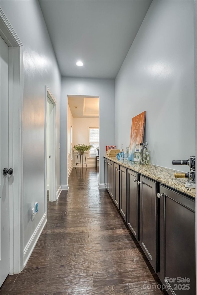 hallway featuring dark wood-type flooring and baseboards