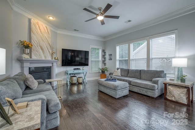 living room with a large fireplace, dark wood-type flooring, visible vents, baseboards, and crown molding