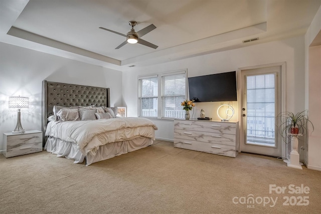 bedroom featuring a tray ceiling, carpet flooring, visible vents, and baseboards