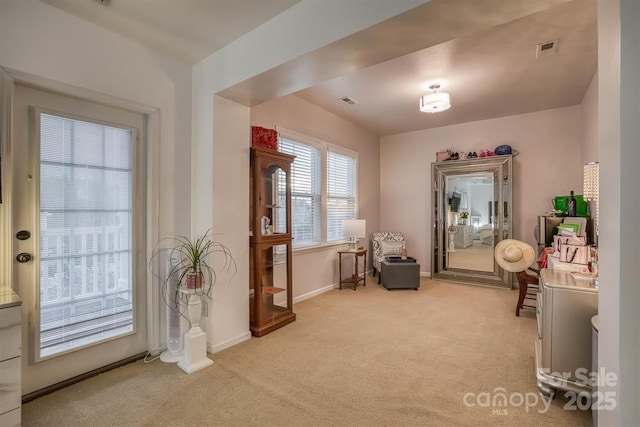 living area featuring light carpet, visible vents, and baseboards