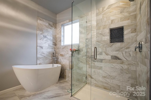 bathroom with marble finish floor, a shower stall, baseboards, and a freestanding bath