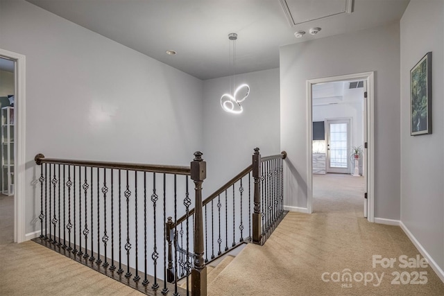 hall with carpet floors, baseboards, visible vents, and an upstairs landing