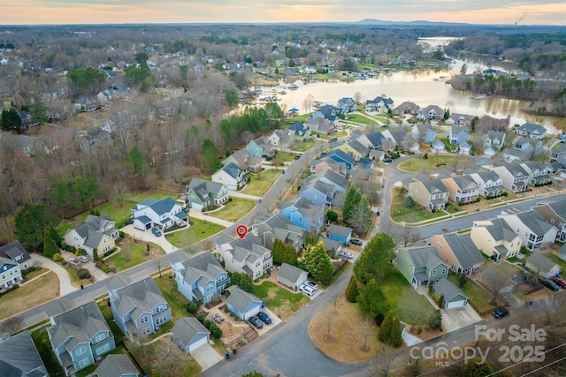 aerial view at dusk featuring a water view and a residential view